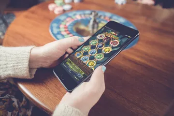 A man focused on his laptop with live stats in the background, highlighting the dedicated sports and gaming features of the LG111 mobile app.