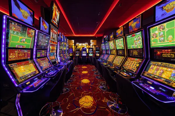 A woman smiling by bright slot machines showing lucky symbols, showcasing the exciting slot offerings at LG111.
